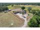 Ranch style home, surrounded by horse paddocks and stables, circular driveway, and mature trees from above at 6709 W Knights Griffin Rd, Plant City, FL 33565