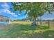 Spacious backyard featuring lush green lawn, mature trees, a tire swing, and playground equipment at 6709 W Knights Griffin Rd, Plant City, FL 33565