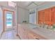 Bathroom with double vanity, a large mirror, and a door leading to an outdoor pool area at 6709 W Knights Griffin Rd, Plant City, FL 33565