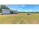A large horse stable with metal siding and multiple stalls, overlooking a grassy paddock and blue skies at 6709 W Knights Griffin Rd, Plant City, FL 33565