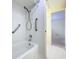 Bathroom featuring a bathtub and shower with safety bars and white tiling at 7307 Summerbridge Dr, Tampa, FL 33634