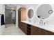 Modern bathroom featuring dual sinks, illuminated mirrors, and a glass-enclosed shower with gray tiling at 777 3Rd N Ave # 1408, St Petersburg, FL 33701