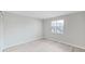 Bright bedroom featuring light gray walls, light wood floors, and a window overlooking the neighborhood at 100 Glennes Ln # 108, Dunedin, FL 34698