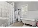 Bathroom features a claw foot tub, tiled shower, storage cabinet, and a window with natural light at 107 W Amelia Ave, Tampa, FL 33602