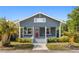 Charming blue home featuring a cozy front porch, red door, and lush landscaping under a clear blue sky at 107 W Amelia Ave, Tampa, FL 33602