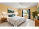 Bright bedroom with yellow walls, a ceiling fan, and a large window with a view of tropical greenery at 11503 Whispering Hollow Dr, Tampa, FL 33635