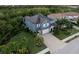 Aerial view of a beautiful blue home with a brick driveway surrounded by lush greenery at 12026 Medley Ter, Lakewood Ranch, FL 34211