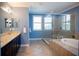 A bathroom featuring a large soaking tub, walk-in shower, dual sinks and a window at 12026 Medley Ter, Lakewood Ranch, FL 34211