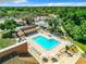 Aerial view of a community pool and lounge area with a background of mature trees and tennis courts at 12920 Wedgewood Way # A, Hudson, FL 34667