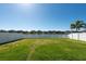 Spacious backyard with manicured lawn, white fence, and a picturesque view of a lake at 13639 Ashlar Slate Pl, Riverview, FL 33579