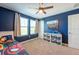 Cozy bedroom with natural light from dual windows, dark blue walls, and toy storage shelves at 13639 Ashlar Slate Pl, Riverview, FL 33579