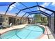 Backyard pool area with a screen enclosure, patio furniture, and views of the well-maintained yard at 16118 Lytham Dr, Odessa, FL 33556