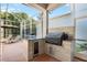 Outdoor kitchen featuring a grill and granite counters, perfect for backyard entertaining by the screened pool at 16629 Sedona De Avila, Tampa, FL 33613