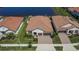 Aerial view showcasing a home's tile roof, double garage, and proximity to a tranquil pond at 17583 Holly Well Ave, Wimauma, FL 33598