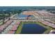 Expansive aerial view of a community with homes surrounding a tranquil pond and future development in the distance at 17583 Holly Well Ave, Wimauma, FL 33598