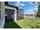 Inviting backyard featuring a screened lanai, well-maintained lawn, and serene lake view with fence at 17583 Holly Well Ave, Wimauma, FL 33598