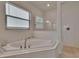 Bright bathroom with large corner soaking tub, glass enclosed shower, and neutral accents at 17583 Holly Well Ave, Wimauma, FL 33598