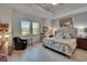 Spacious main bedroom featuring light wood floors, two windows, and comfortable seating area at 17583 Holly Well Ave, Wimauma, FL 33598