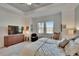 Bright main bedroom with a tv, two windows, comfortable seating and light wood floors at 17583 Holly Well Ave, Wimauma, FL 33598