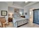 Well-lit main bedroom with tray ceiling, rocking chair, and ensuite bathroom access at 17583 Holly Well Ave, Wimauma, FL 33598