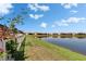 Picturesque view of a pond, framed by lush greenery and a white fence, ideal for waterfront living at 17583 Holly Well Ave, Wimauma, FL 33598