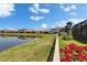 Waterfront property with a charming fence and vibrant bougainvillea, offering serene views at 17583 Holly Well Ave, Wimauma, FL 33598