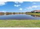 Scenic pond view reflecting the surrounding homes under a bright, partly cloudy sky at 17583 Holly Well Ave, Wimauma, FL 33598