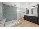 Modern bathroom featuring a glass shower with geometric tile and a dual vanity with sleek black cabinets at 17730 Long Point Dr, Redington Shores, FL 33708