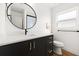 Bathroom vanity with black cabinetry, quartz countertop, round mirror, and black fixtures at 17730 Long Point Dr, Redington Shores, FL 33708