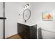 Bathroom vanity with black cabinetry, quartz countertop, round mirror, black fixtures and toilet at 17730 Long Point Dr, Redington Shores, FL 33708