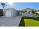 Inviting home featuring a manicured front yard, paver driveway, and an attached garage at 17730 Long Point Dr, Redington Shores, FL 33708
