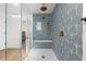 Geometric blue tiled shower featuring a built in bench and glass surround in a bright bathroom at 17730 Long Point Dr, Redington Shores, FL 33708
