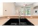 Close-up of a kitchen sink and countertop with a view of the living area and pool at 18310 Bankston Pl, Tampa, FL 33647
