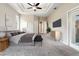 Staged main bedroom with tray ceilings, carpet, neutral walls, a TV, and access to the outdoors at 18310 Bankston Pl, Tampa, FL 33647