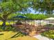 Community playground featuring a swing set and covered play structure, surrounded by mature trees and a white picket fence at 18310 Bankston Pl, Tampa, FL 33647