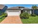 Charming home featuring a brick driveway, well-maintained lawn, and elegant architectural details at 19442 Sea Glass Cir, Land O Lakes, FL 34638