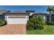 Charming home featuring a brick-paved driveway, a two-car garage, and lush landscaping creating a welcoming curb appeal at 19442 Sea Glass Cir, Land O Lakes, FL 34638