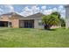 The backyard features green grass, beautiful palm trees, and a screened lanai at 20606 Whitewood Way, Tampa, FL 33647