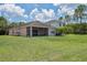 Green backyard featuring a screened lanai, palm trees, and fresh-cut grass at 20606 Whitewood Way, Tampa, FL 33647