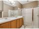 Well-lit bathroom featuring double sinks, framed mirror, and glass door shower at 20606 Whitewood Way, Tampa, FL 33647