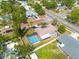 Aerial view of a home with a screened-in pool, lush landscaping, and a fenced backyard at 225 Cevera Dr, Dunedin, FL 34698