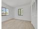 Well-lit, empty bedroom with a large closet, two windows, and light wood floors at 225 Cevera Dr, Dunedin, FL 34698