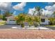 Charming single-story home with lush tropical landscaping, a brick-paved street, and a white picket fence at 225 Cevera Dr, Dunedin, FL 34698