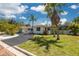 Charming single-story home with lush tropical landscaping, a brick-paved street, and a white picket fence at 225 Cevera Dr, Dunedin, FL 34698