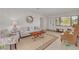 Bright living room featuring a cozy couch, floral chair, wooden coffee table, and natural light from the front window at 225 Cevera Dr, Dunedin, FL 34698