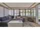 Comfortable sunroom with natural light, a large sectional sofa, a vintage coffee table, and a stylish bar cart at 225 Cevera Dr, Dunedin, FL 34698