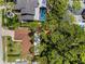 Aerial view showcasing the layout of the home, landscaped yard, and neighboring properties and lush greenery at 2486 Indian E Trl, Palm Harbor, FL 34683