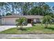 Charming single-story home featuring a two-car garage, well-manicured lawn, and tropical landscaping at 2486 Indian E Trl, Palm Harbor, FL 34683