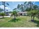 Charming single-story home with a spacious green lawn, palm trees, and mature trees at 2486 Indian E Trl, Palm Harbor, FL 34683