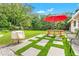 Lush backyard featuring grass, stone walkway, and a red umbrella over a picnic table at 251 Dunbridge Dr, Palm Harbor, FL 34684